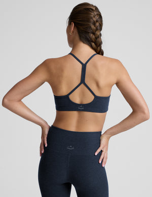 Woman wearing a navy sports bra and leggings against a plain background. 