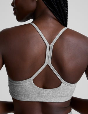 Woman wearing a gray sports bra and leggings on a light gray background. 