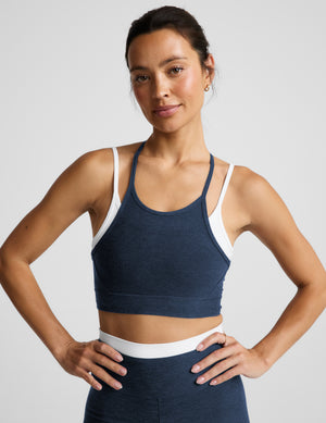 Woman wearing a navy layered bra and leggings against a plain background. 