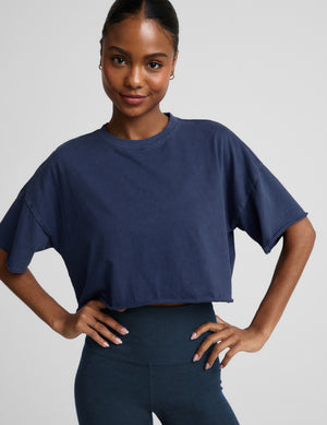 Woman wearing a navy blue cropped t-shirt and navy biker shorts against a plain background. 