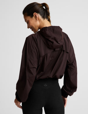 Woman wearing a brown jacket and black leggings against a plain background. 