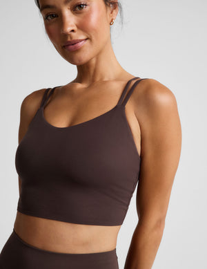 Woman wearing a brown cropped tank and midi leggings on an plain studio background. 