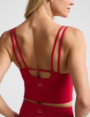 A woman shown from the back wearing a bright red sports bra and matching high-waisted bottoms against a light gray studio background.