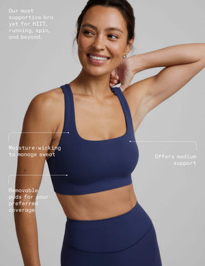 Woman wearing a blue sports bra and blue biker shorts against a plain background. 