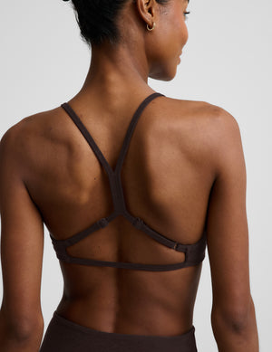 Woman wearing a brown bra and brown leggings against a plain background. 