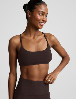 Woman wearing a brown bra and brown leggings against a plain background. 