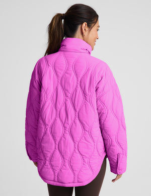 A woman wearing a bright pink quilted jacket, shown from the back against a light gray studio background.