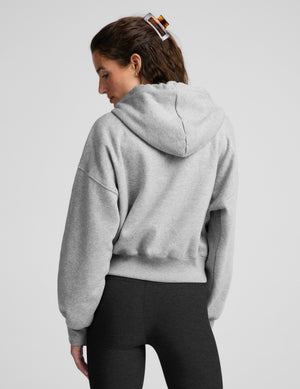 Woman wearing a green zip-up fleece sweatshirt and black leggings against a plain background. 