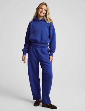 A woman modeling a matching royal blue sweatshirt and sweatpants lounge set against a light gray studio background.