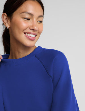 A woman modeling a matching royal blue sweatshirt and jogger pants set against a light gray studio background.