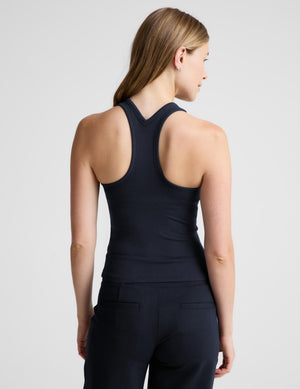 A woman modeling a dark navy sleeveless athletic tank top and matching high-waisted leggings against a light gray studio background.