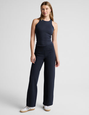 A woman modeling a dark navy sleeveless athletic tank top and matching high-waisted leggings against a light gray studio background.