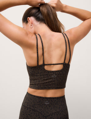 A woman viewed from behind wearing a dark brown cropped tank and matching leggings with a subtle leopard print, featuring a unique multi-strap back design on the bra.