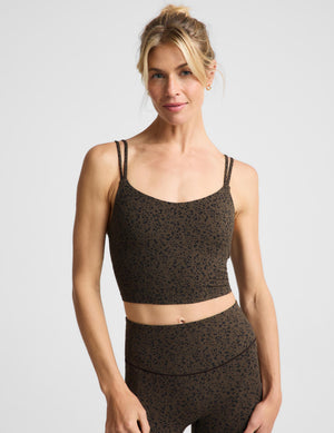 A woman modeling a matching activewear set featuring a dark brown and black leopard print cropped tank and high-waisted leggings against a light gray studio background.