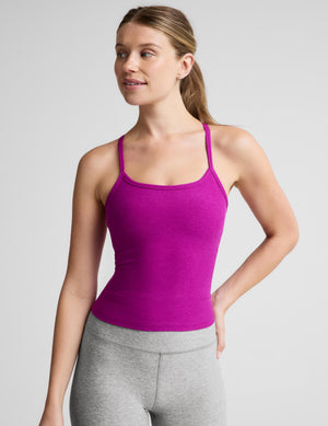 A woman wearing a bright magenta-pink ribbed tank top and heather gray leggings, standing against a light gray studio background.