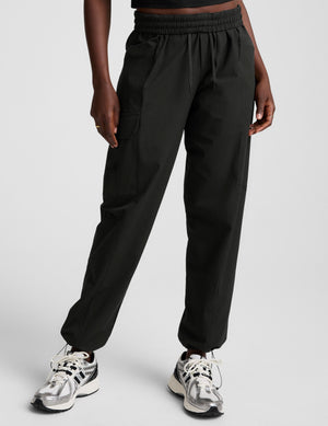 model wearing a black t-shirt and black cargo style pants on a white background. 