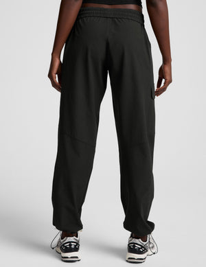 model wearing a black t-shirt and black cargo style pants on a white background. 