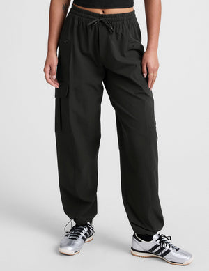 Woman wearing Brown Peak Pant™ with a black crop top and silver sneakers, featuring an elastic waist and cargo pockets.