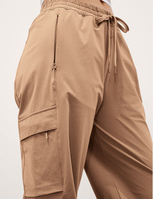 Woman wearing beige cargo pants on a plain background. 