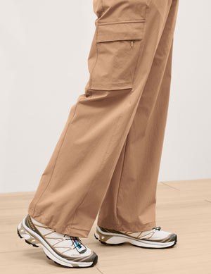 Woman wearing beige cargo pants on a plain background. 