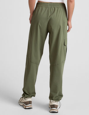 Rear view of the olive green Peak Pant with an elastic waistband, side cargo pocket, and bungee hem at the ankles.