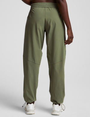 model wearing olive green cargo pants on a white background. 