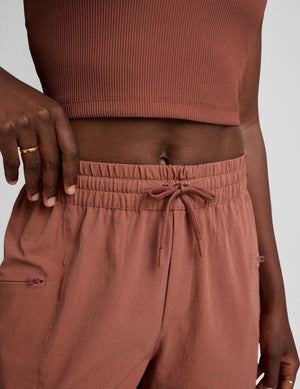 Close-up of the Java brown Peak Pant showing the gathered elastic waistband, drawstring, and zippered cargo pocket.