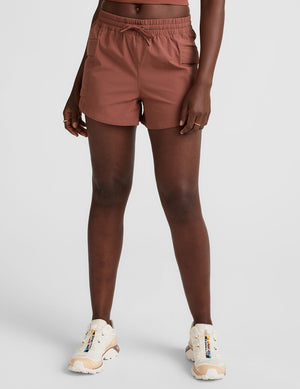 model wearing orange shorts on a light gray background. 