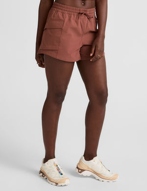 model wearing orange shorts on a light gray background. 