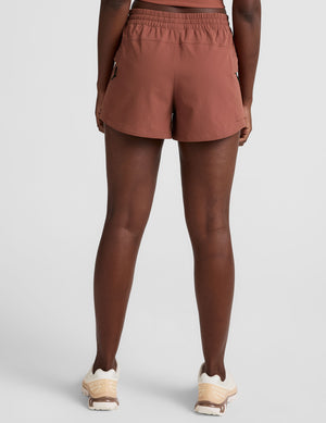 model wearing orange shorts on a light gray background. 