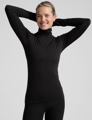 model wearing a black turtleneck shirt against a plain background. 