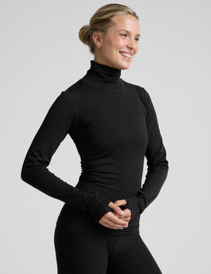 model wearing a black turtleneck shirt against a plain background. 