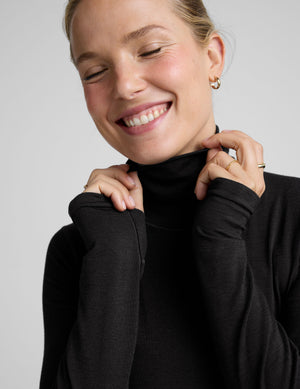 model wearing a black turtleneck shirt against a plain background. 