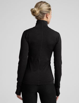 model wearing a black turtleneck shirt against a plain background. 