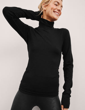 model wearing a black turtleneck shirt against a plain background. 