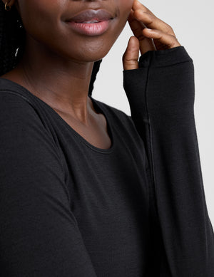 model wearing a black long sleeve crewneck top against a plain background. 