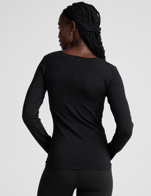 model wearing a black long sleeve crewneck top against a plain background. 