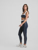 navy blue high-waisted midi leggings with white contrast piping on side of leg and around waistband. 