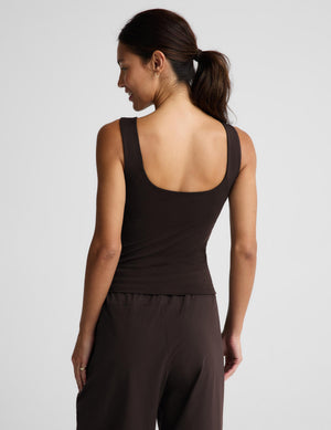 A woman modeling a dark brown sleeveless tank top and matching dark brown pants against a light gray studio background.