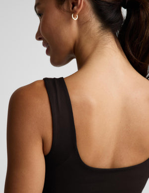 A woman modeling a dark brown sleeveless tank top and matching dark brown pants against a light gray studio background.