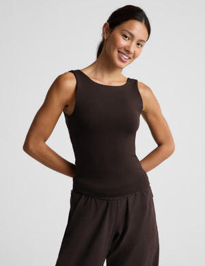 A woman modeling a dark brown sleeveless tank top and matching dark brown pants against a light gray studio background.